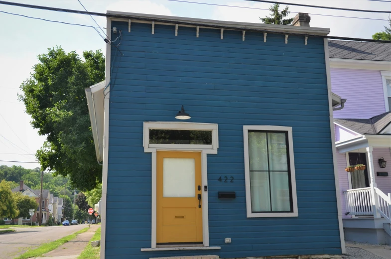 the bright yellow door is in front of a blue house