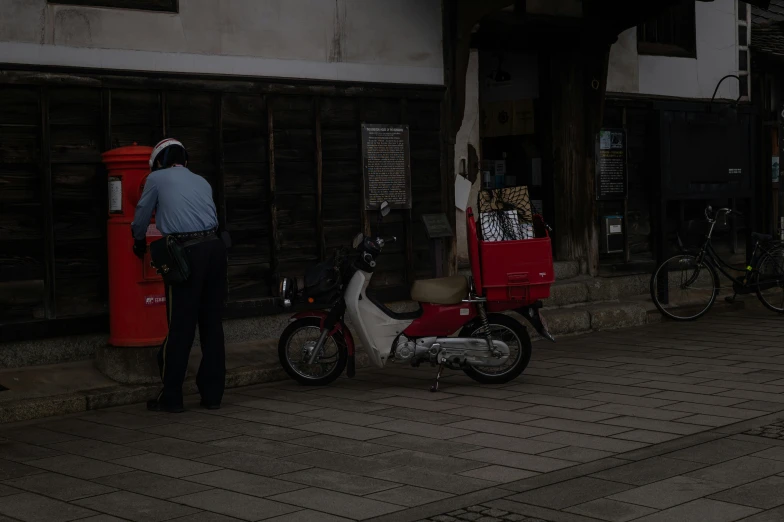 a man stands next to a scooter next to a wall