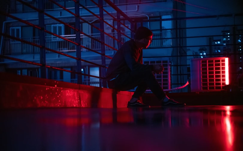 a person sitting on a building ledge in the night