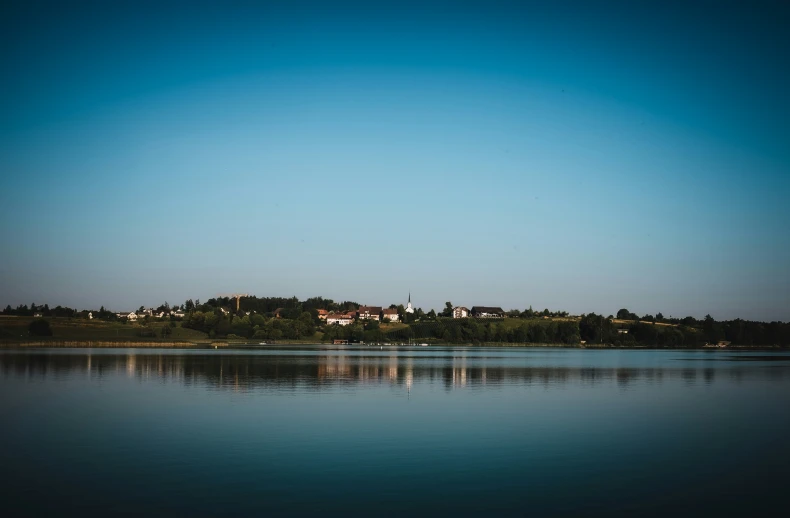 a calm lake with a small village in the background