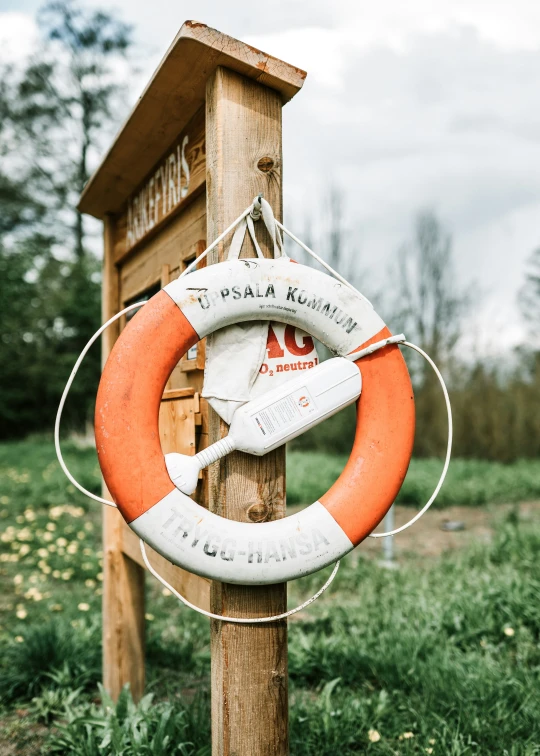 a life preserver sits on top of a wooden post in the grass