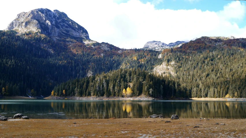 mountain peaks with a lake and grassy field