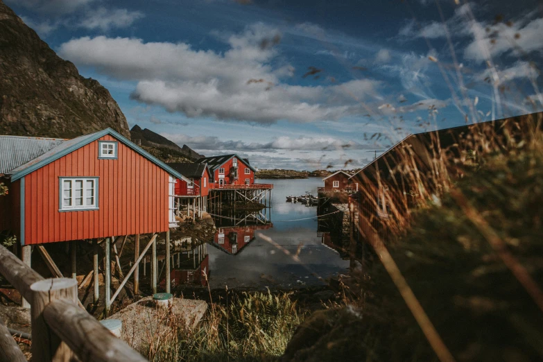 some red houses are by the water near some hills
