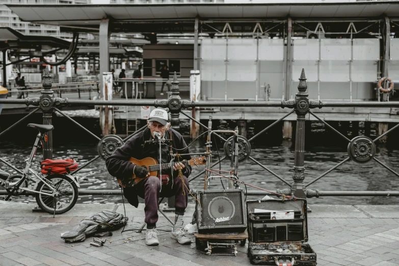 a man sitting on a ledge playing an acoustic guitar