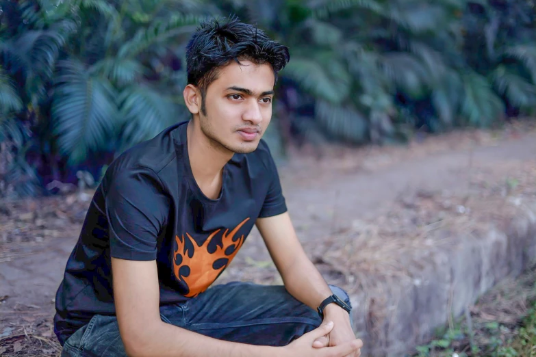 a young man poses while crouching on a hill