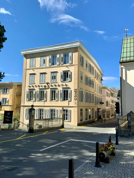 a tan building with many windows is next to a parking lot