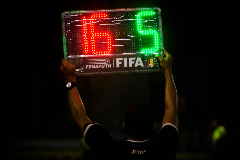 a man holding up a large soccer score board
