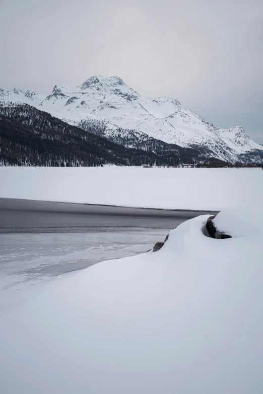 snow covered river bed with mountains in background