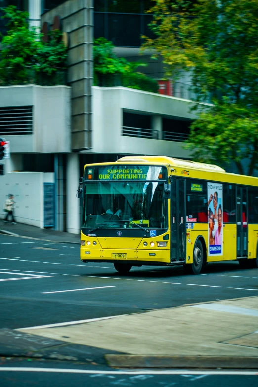 a yellow bus driving down a street past some tall buildings