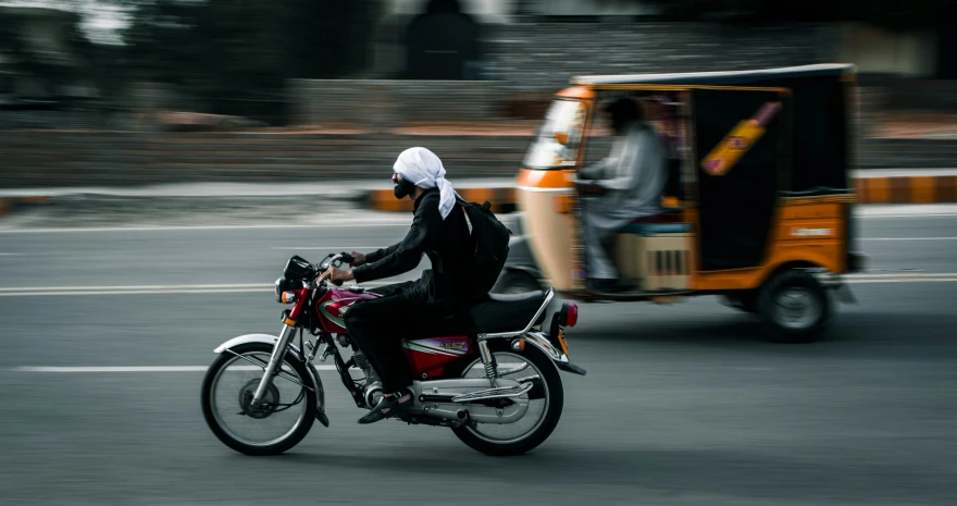 a motorcycle and a person on a street with a taxi behind them