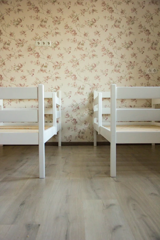 two wooden chairs against the wall with flowery wallpaper