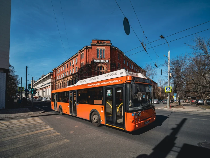 the orange and white bus is driving down the street