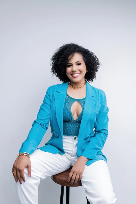 an african woman sits in a chair wearing a blue jacket