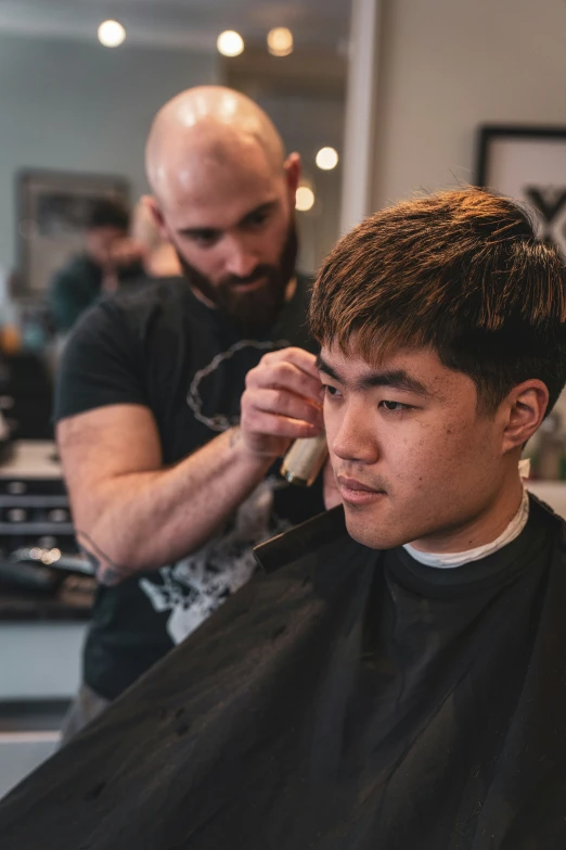 a man is having his haircut cut by an older man