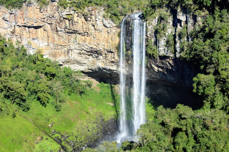 waterfall surrounded by trees and mountains with grass