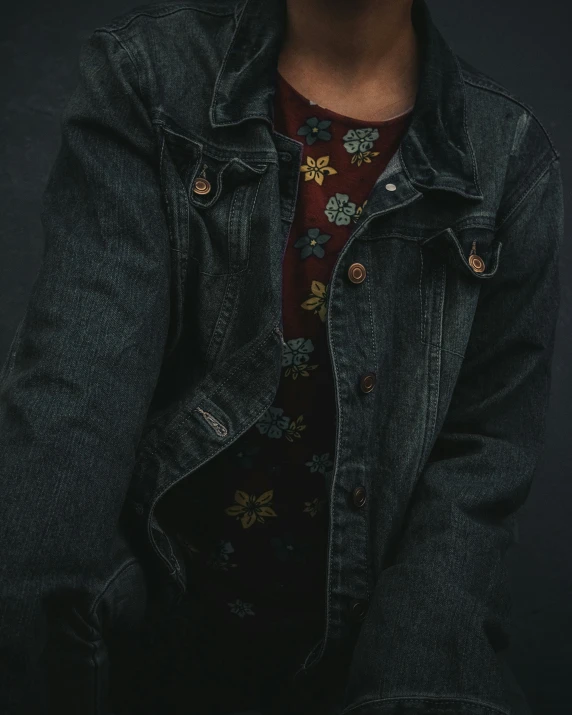 a man wearing a jean jacket with a colorful floral pattern