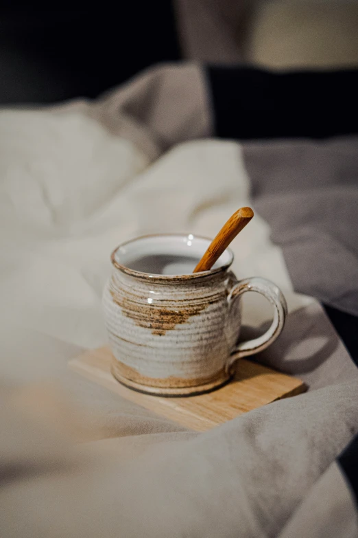 a coffee mug on a plate with a wooden spoon