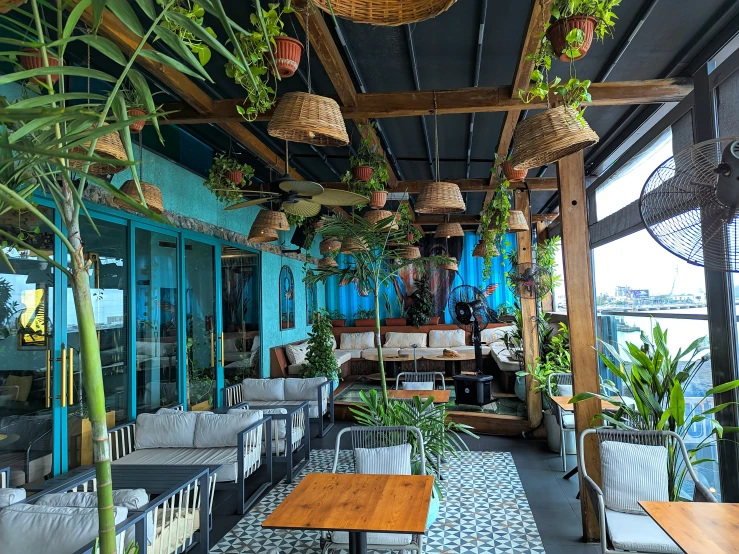 a restaurant area with lots of tables, chairs and hanging plants