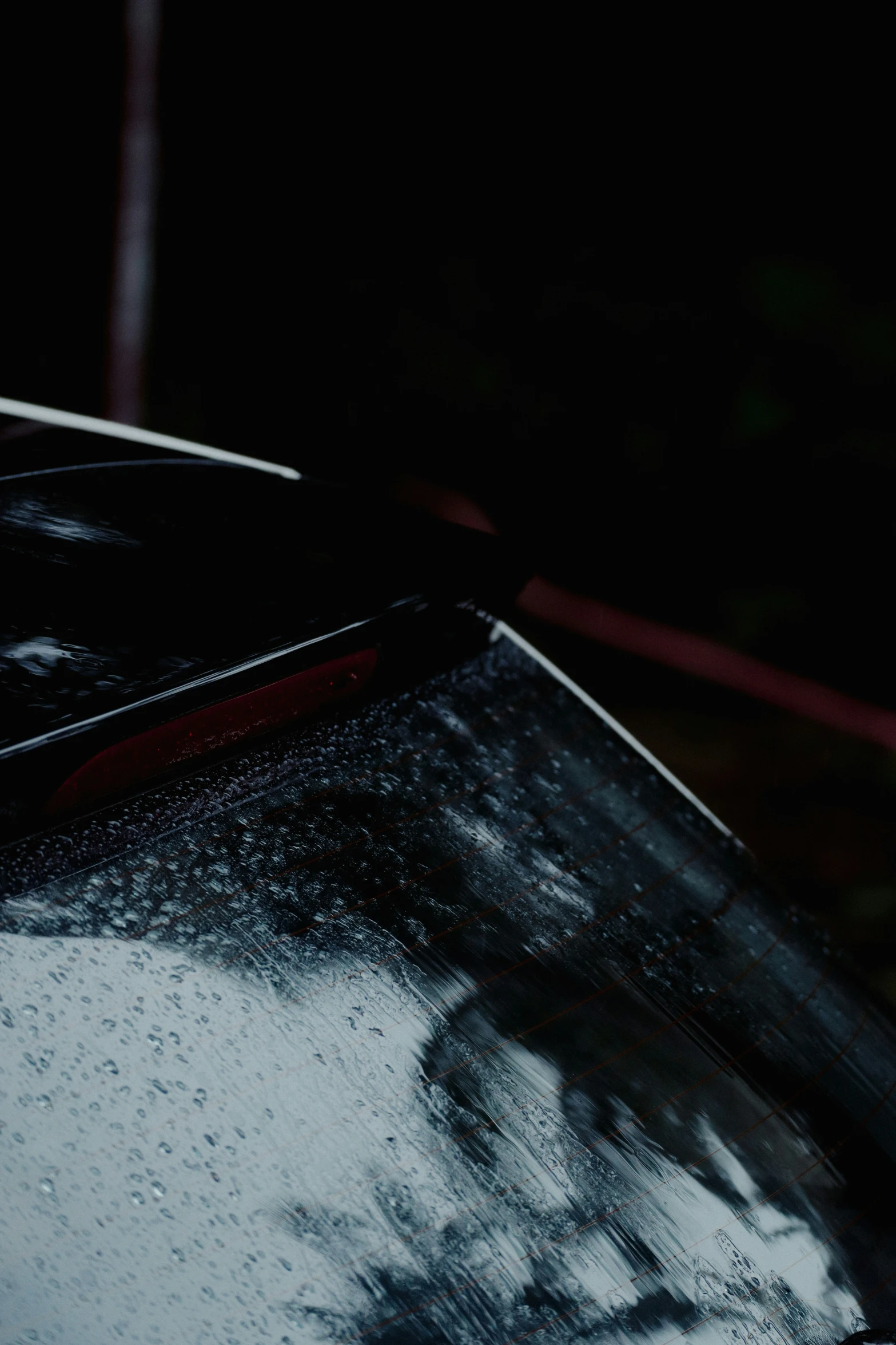 a black car parked in the rain at night