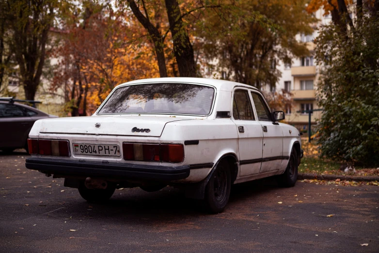 an old, dirty car parked on the street in a residential neighborhood