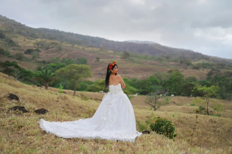 a woman in a white dress is posing on a hill