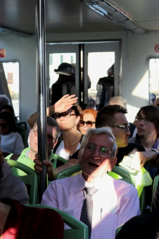 an older gentleman sitting in a crowded bus