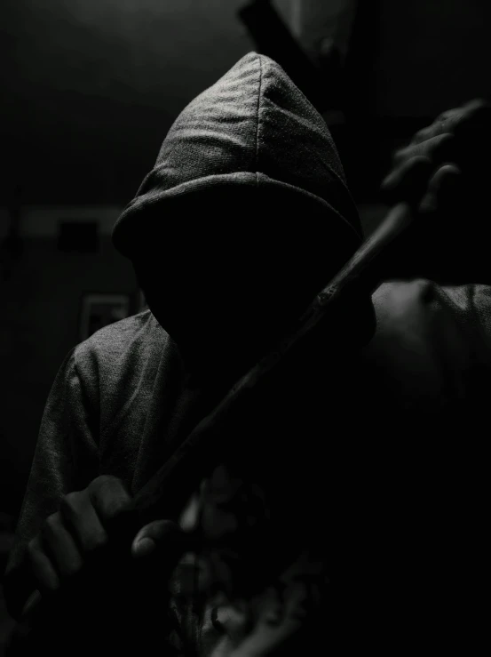 a person with a hood and bat behind him