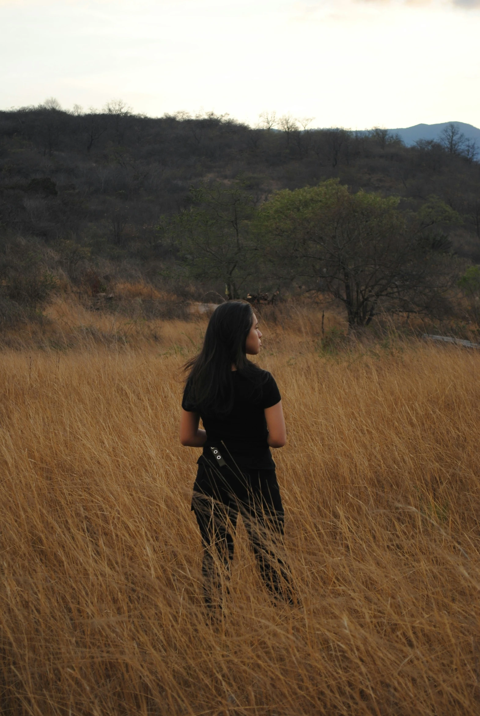 a woman standing in tall dry grass in the wilderness