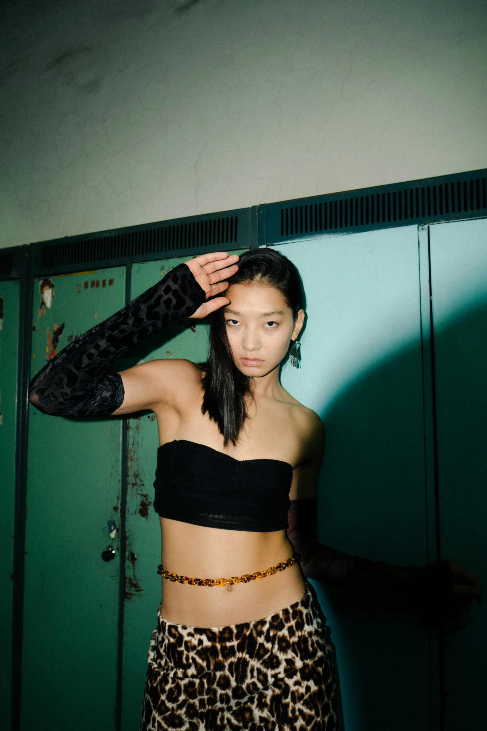 a woman standing in front of lockers wearing leopard pants and a black 