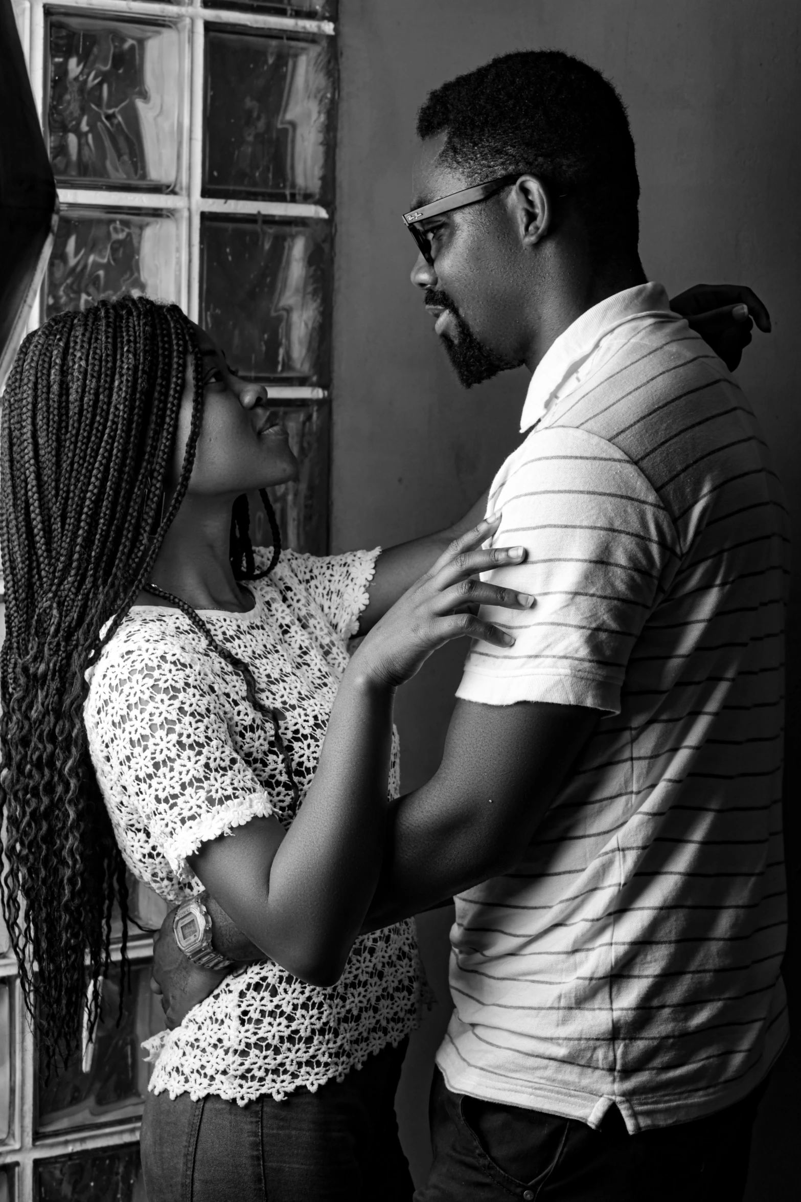 the man is holding the woman's neck while she puts on her earrings