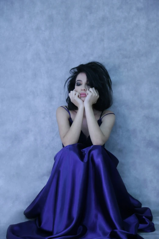 a woman sitting in front of a blue background