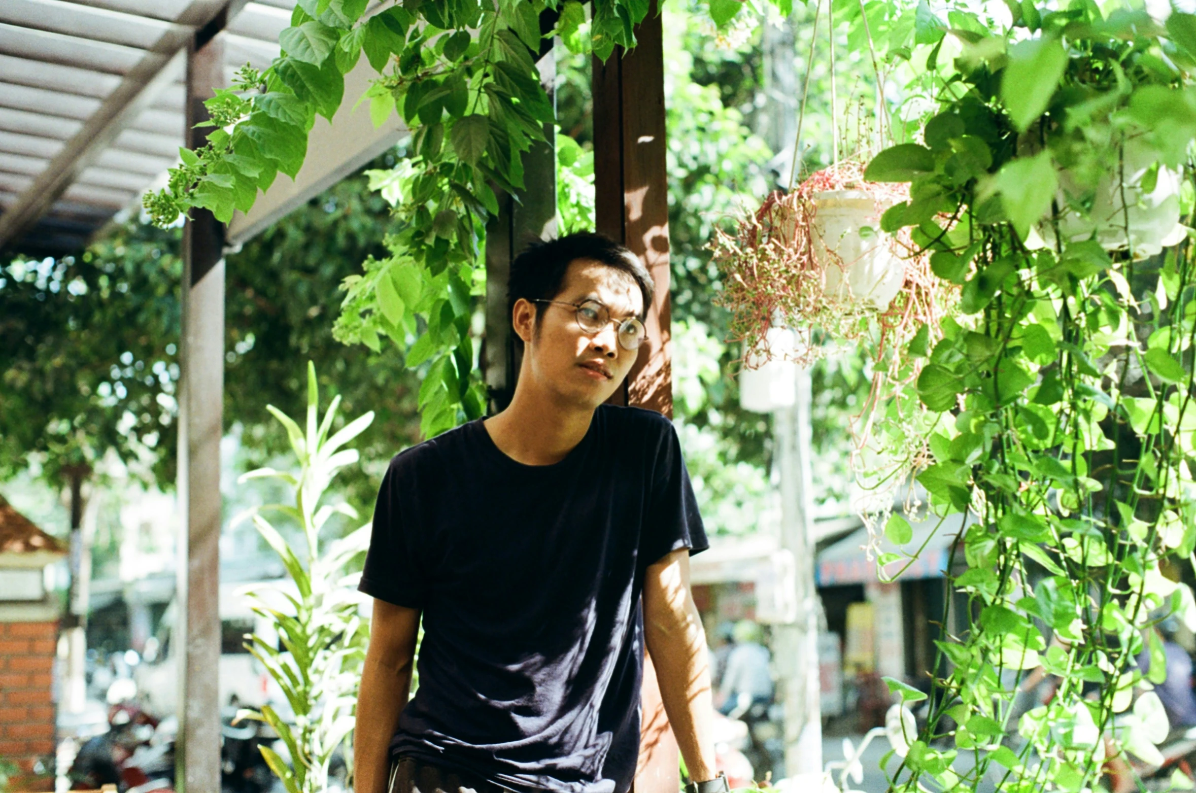 a young man talks on the phone underneath a green tree