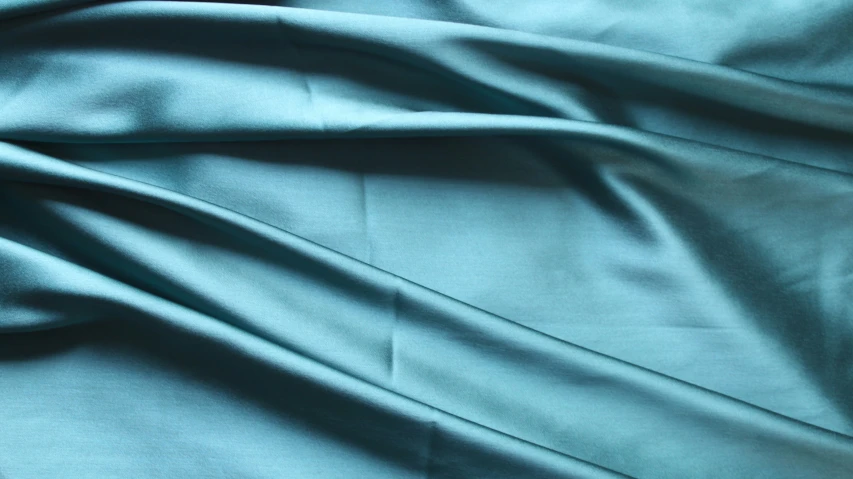 closeup of a plain teal colored satin sheet