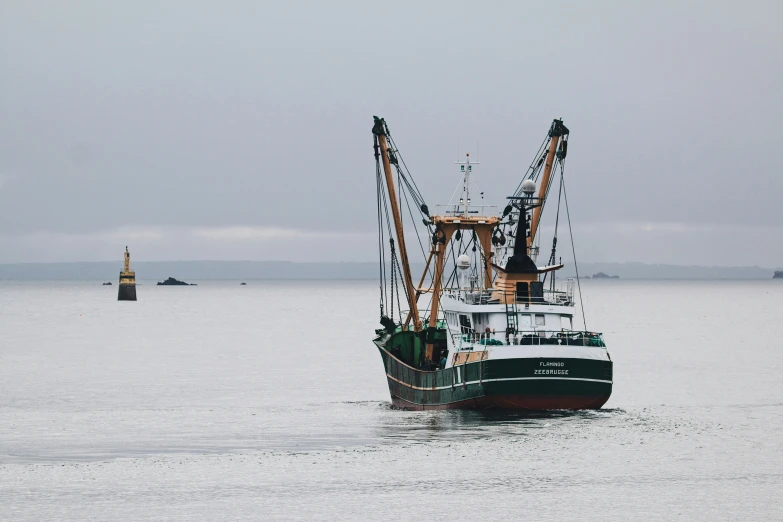 a green and white fishing boat sailing in the water