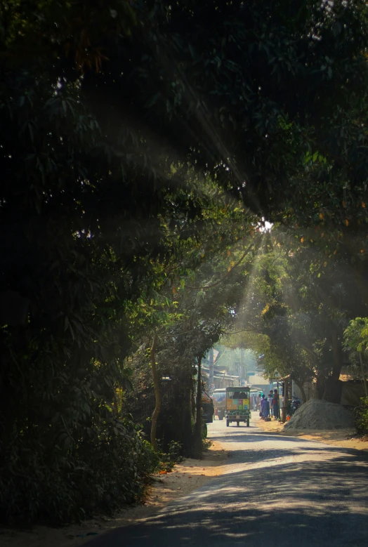 the sun shines through a green arch in the middle of the street