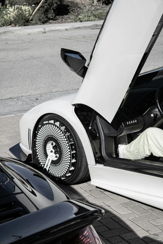 white car door open on asphalt roadway with other cars