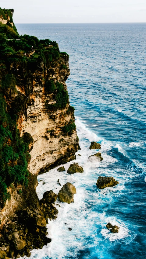 the ocean is blue and is rocky cliff face