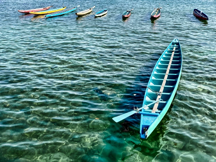 a rowboat is in the water with two rows of canoes behind it