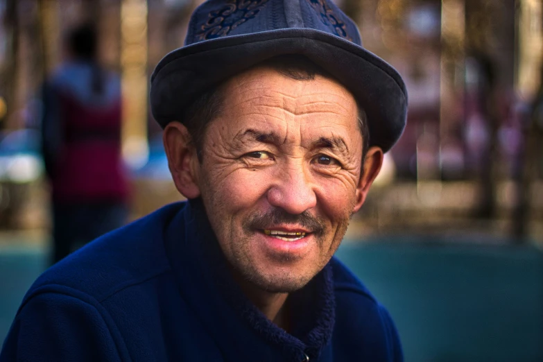 the smiling man wearing a hat is standing in a street