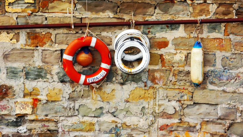 two life saving devices hanging from wall and beside a red round life preserver