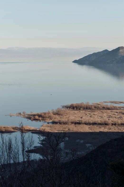 a lake near mountains and trees on a sunny day