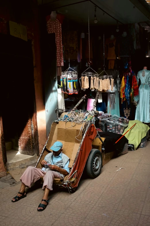 a person sitting in a cart near many clothing on display