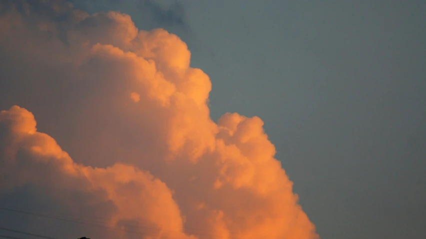 a plane is in the air against the background of orange clouds