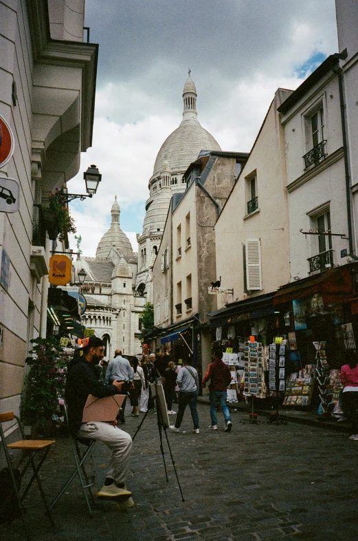 some people walking in a small street with a church in the background