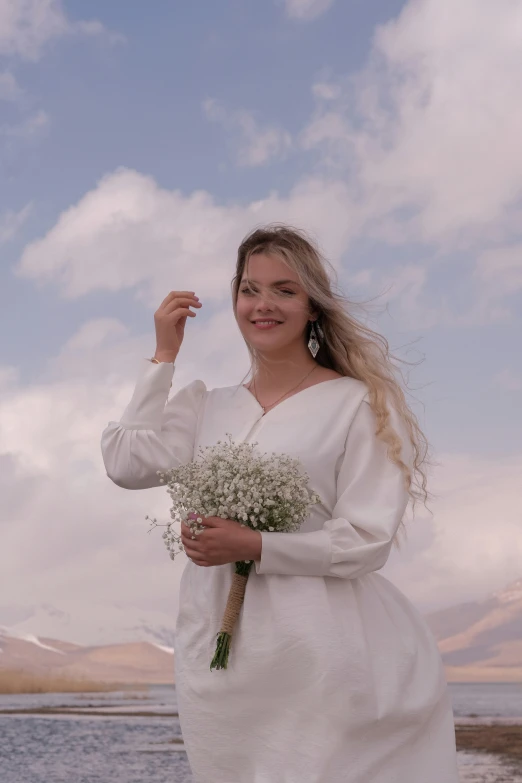 a woman in white standing by a body of water