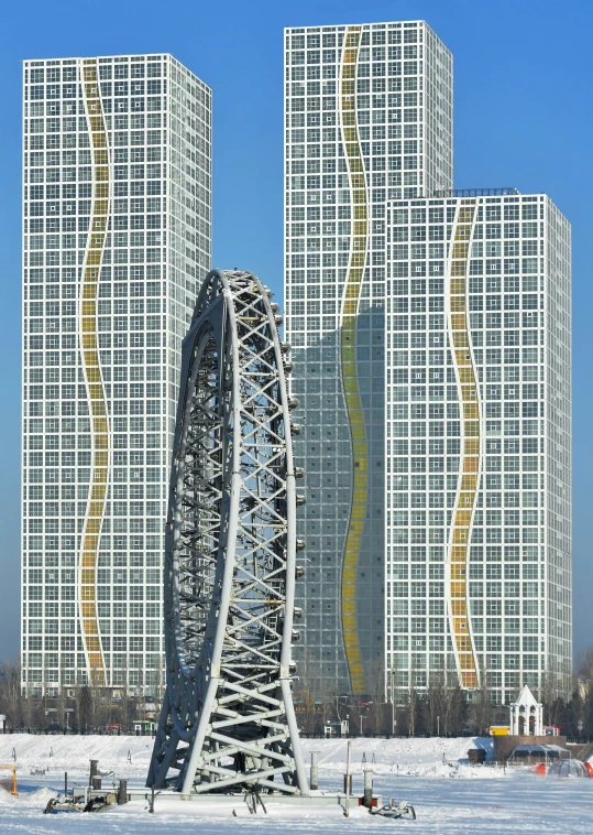 snow covered field with building in background and large ferris wheel with buildings in the distance