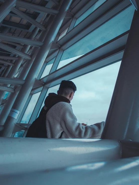 a man standing in front of a window looking at the sky