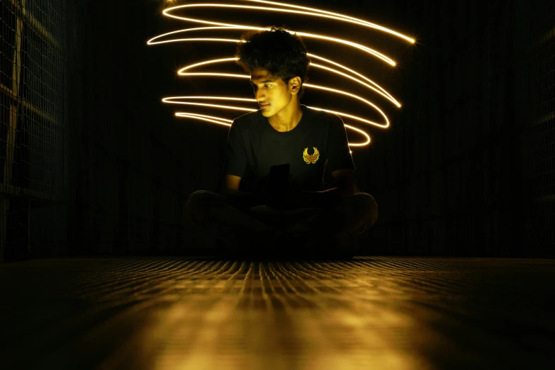 a young man sitting on the floor looking at his cell phone