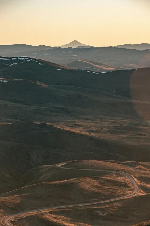 a airplane flying over a large hill side in the desert