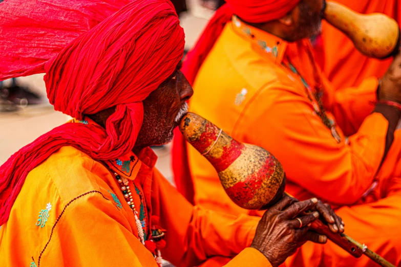 three people in orange dresses are playing musical instruments